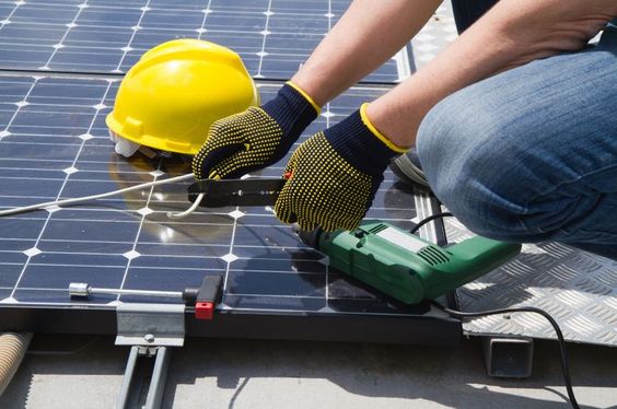 Entreprise de rénovation et d'énergies Calvados - Technicien installant des panneaux photovoltaïques sur un toit.