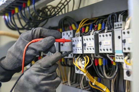 Entreprise de rénovation et d'énergies Calvados - Électricien installant des câbles électriques dans un bâtiment commercial.
