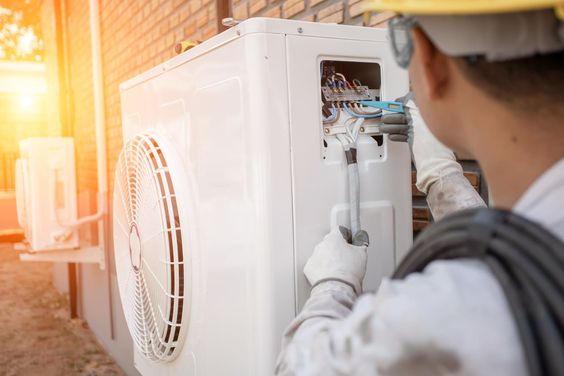 Technicien installant une pompe à chaleur air-air dans une maison pour améliorer l'efficacité énergétique.